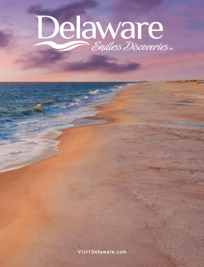Delaware Travel Guide: A scenic view of the Delaware coastline featuring sand dunes and a historic lighthouse under a blue sky.
